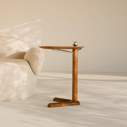 Trilo wooden side table with sculptural three-leg base placed beside a modern curved sofa in a minimalist living room