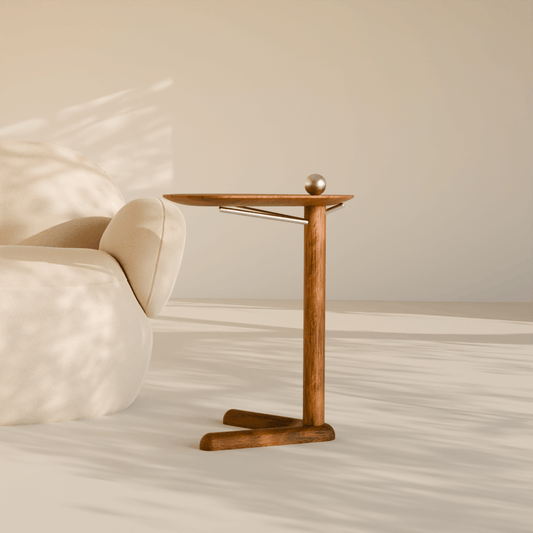 Trilo wooden side table with sculptural three-leg base placed beside a modern curved sofa in a minimalist living room